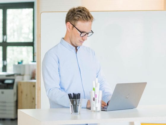 Mann vor Whiteboard an apple MacBook