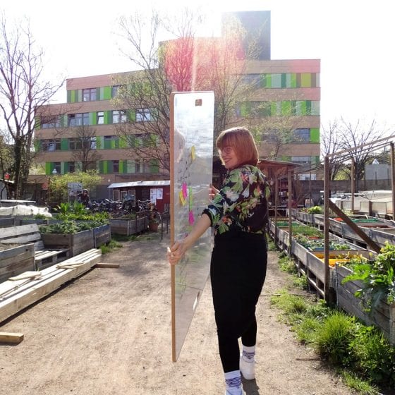 WildBoard Design-Whiteboard wird von einer Frau im himmelbeet Gemeinschaftsgarten getragen
